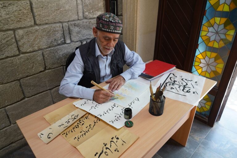 Calligraphe âgé écrivant en arabe au calame