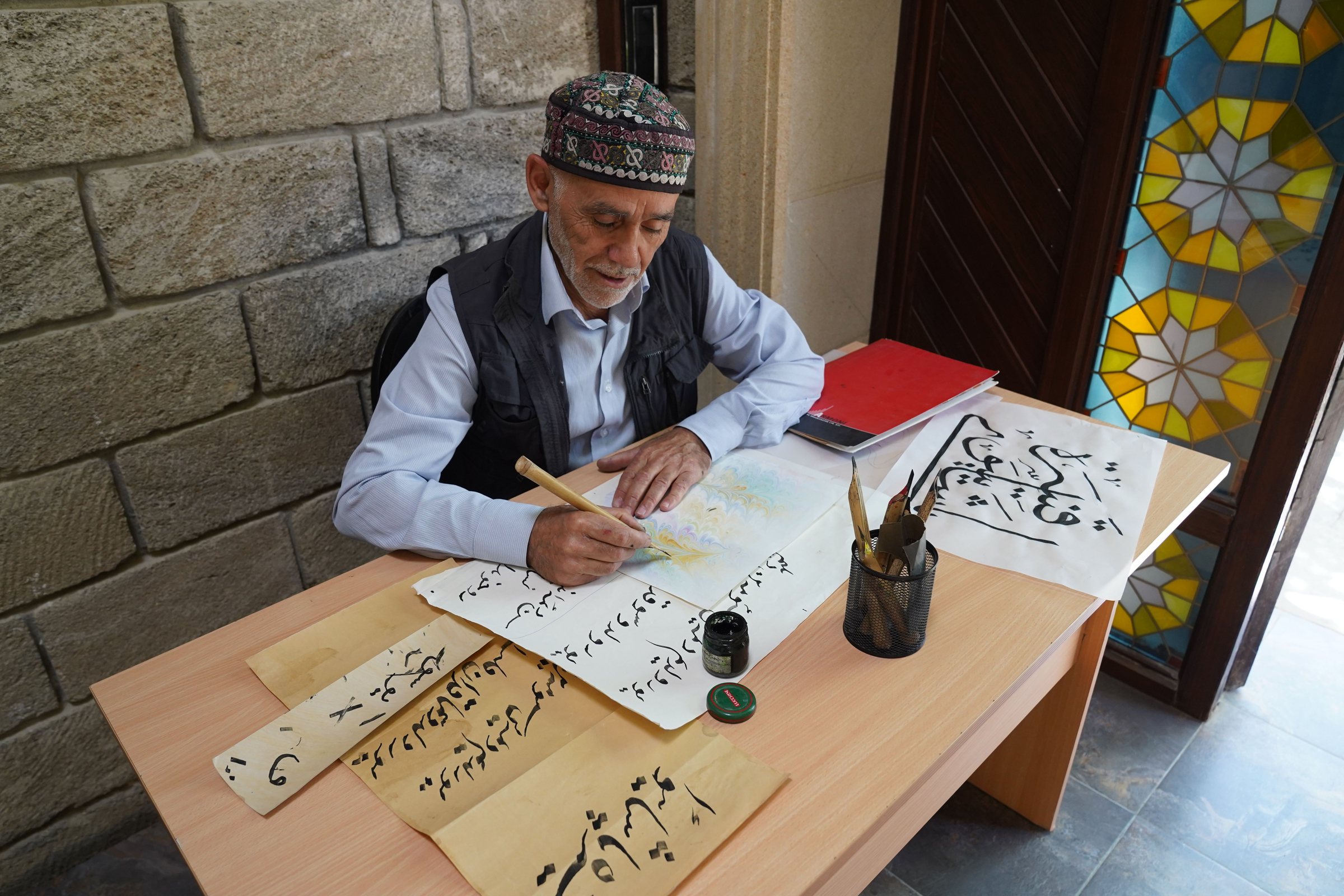 Calligraphe âgé écrivant en arabe au calame