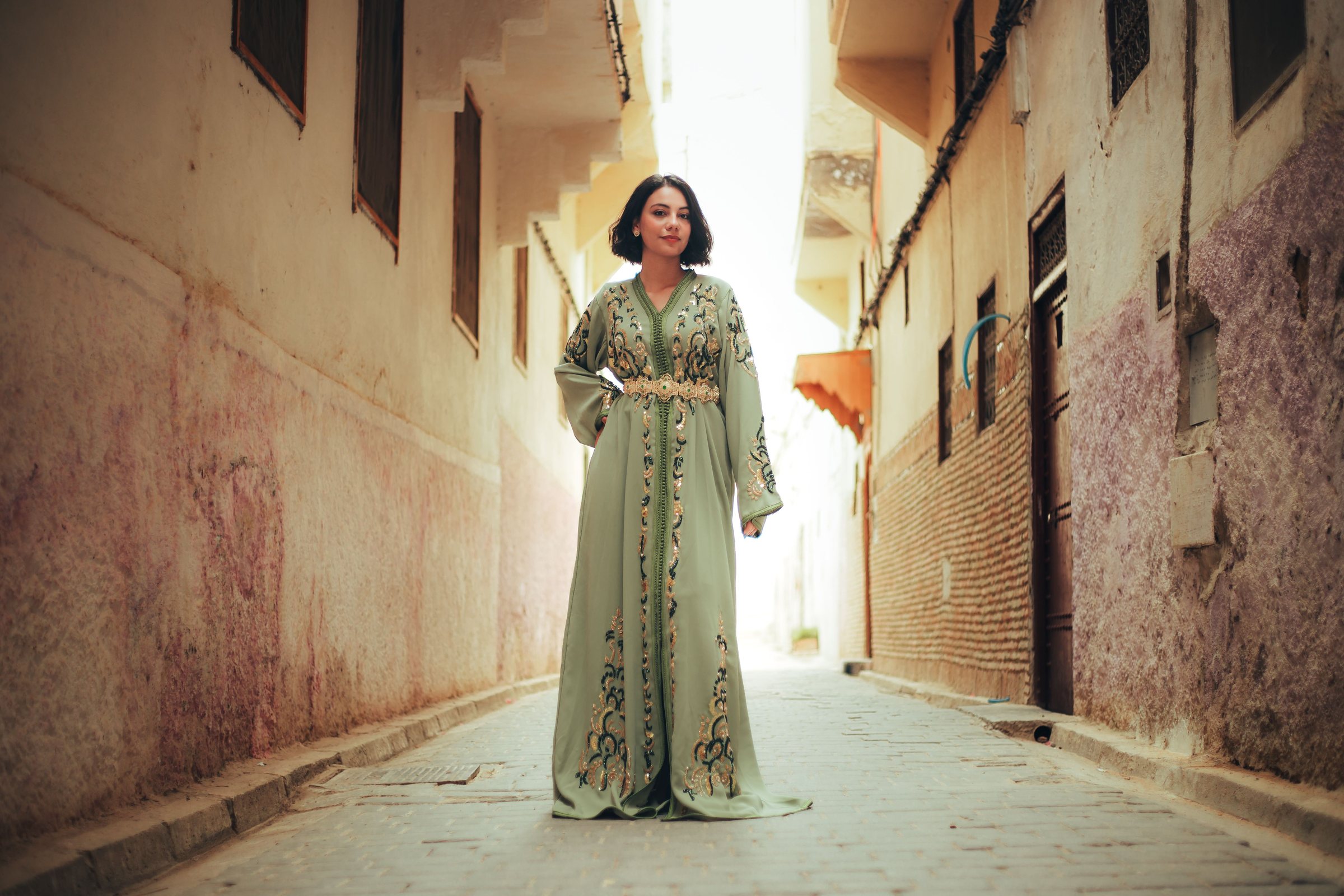 Femme en caftan brodé dans une ruelle de médina