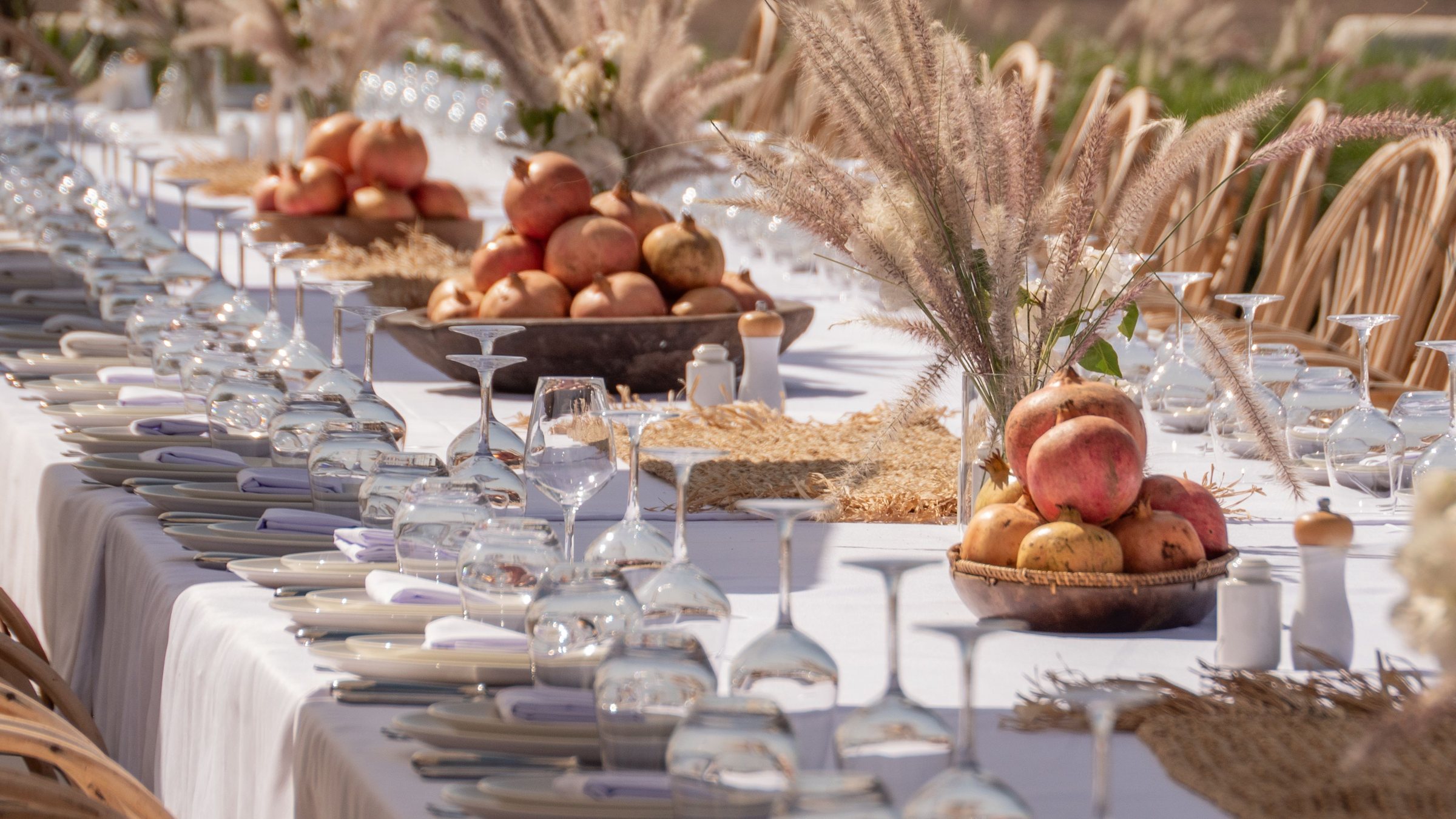 Longue table de banquet blanche avec grenades et herbes de la pampa