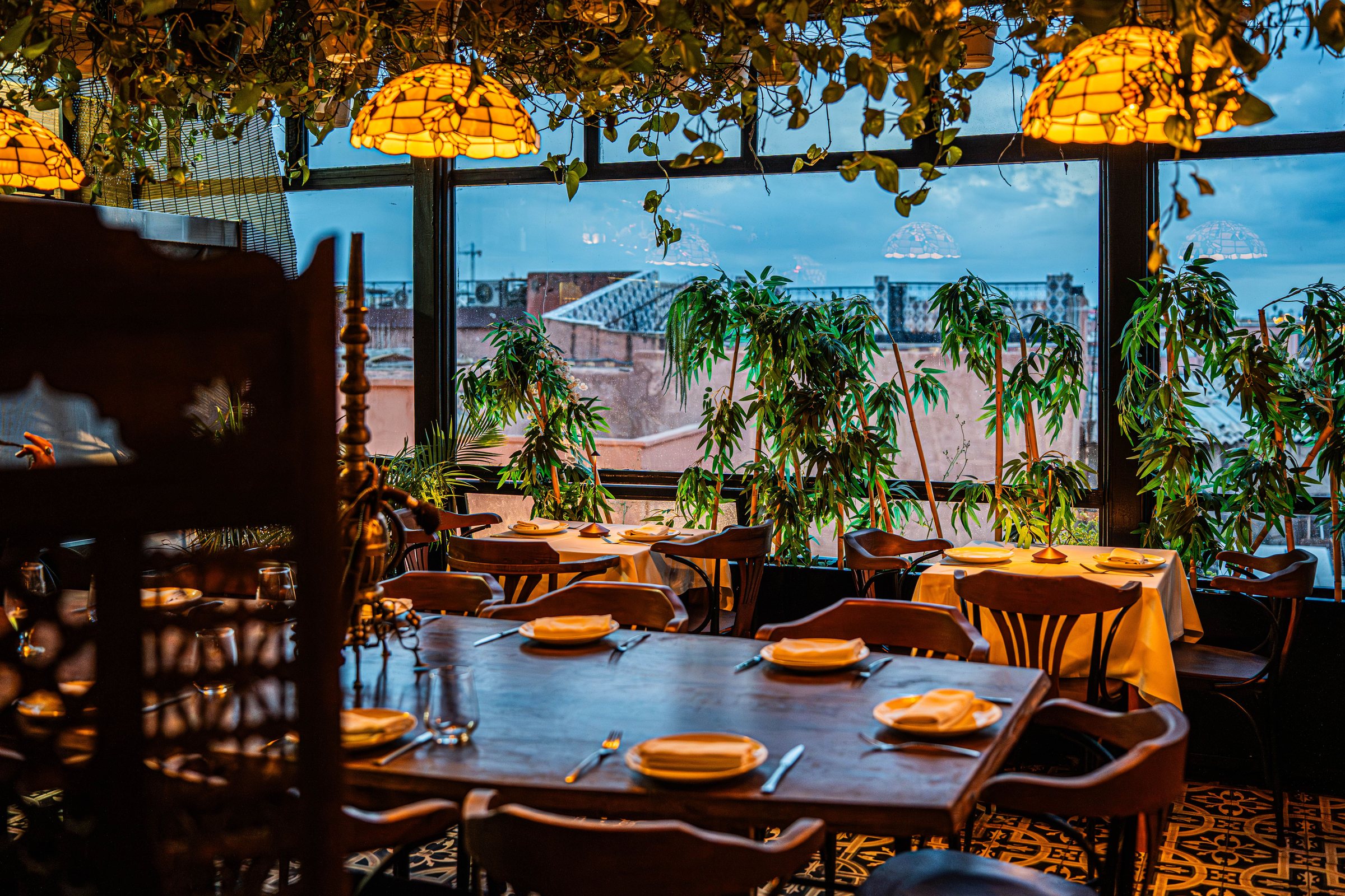 Salle de restaurant aux lampes Tiffany avec vue sur les toits