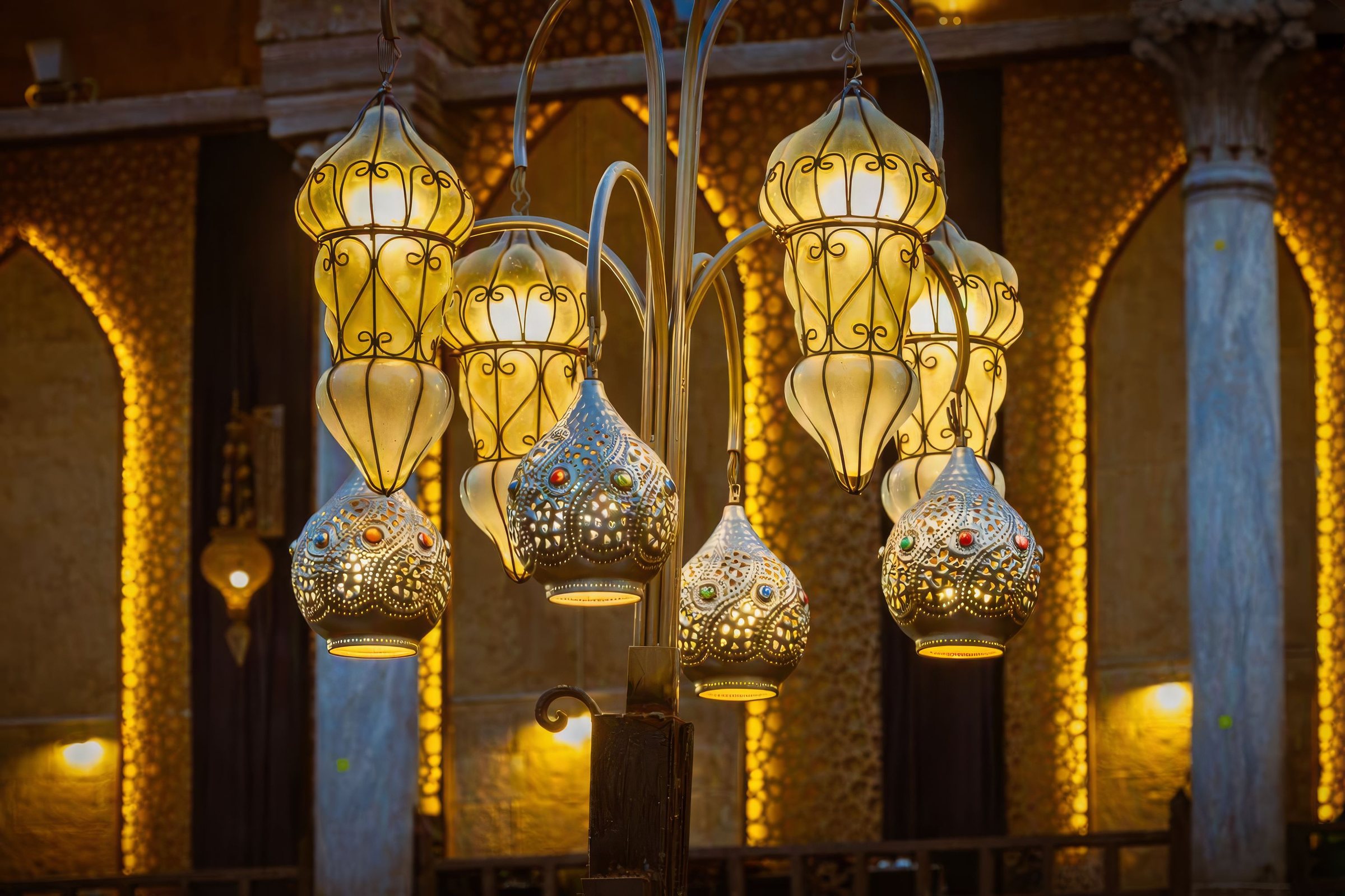Grappe de lanternes marocaines allumées sous des arcades