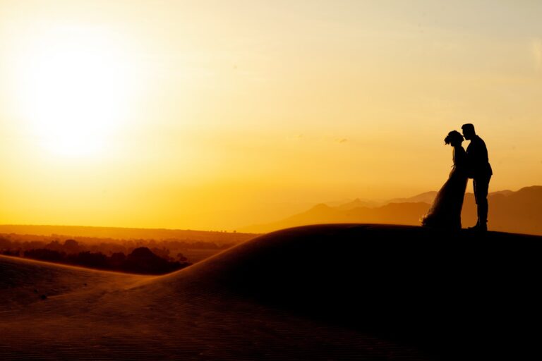 Silhouette d'un couple de mariés sur une dune au coucher du soleil