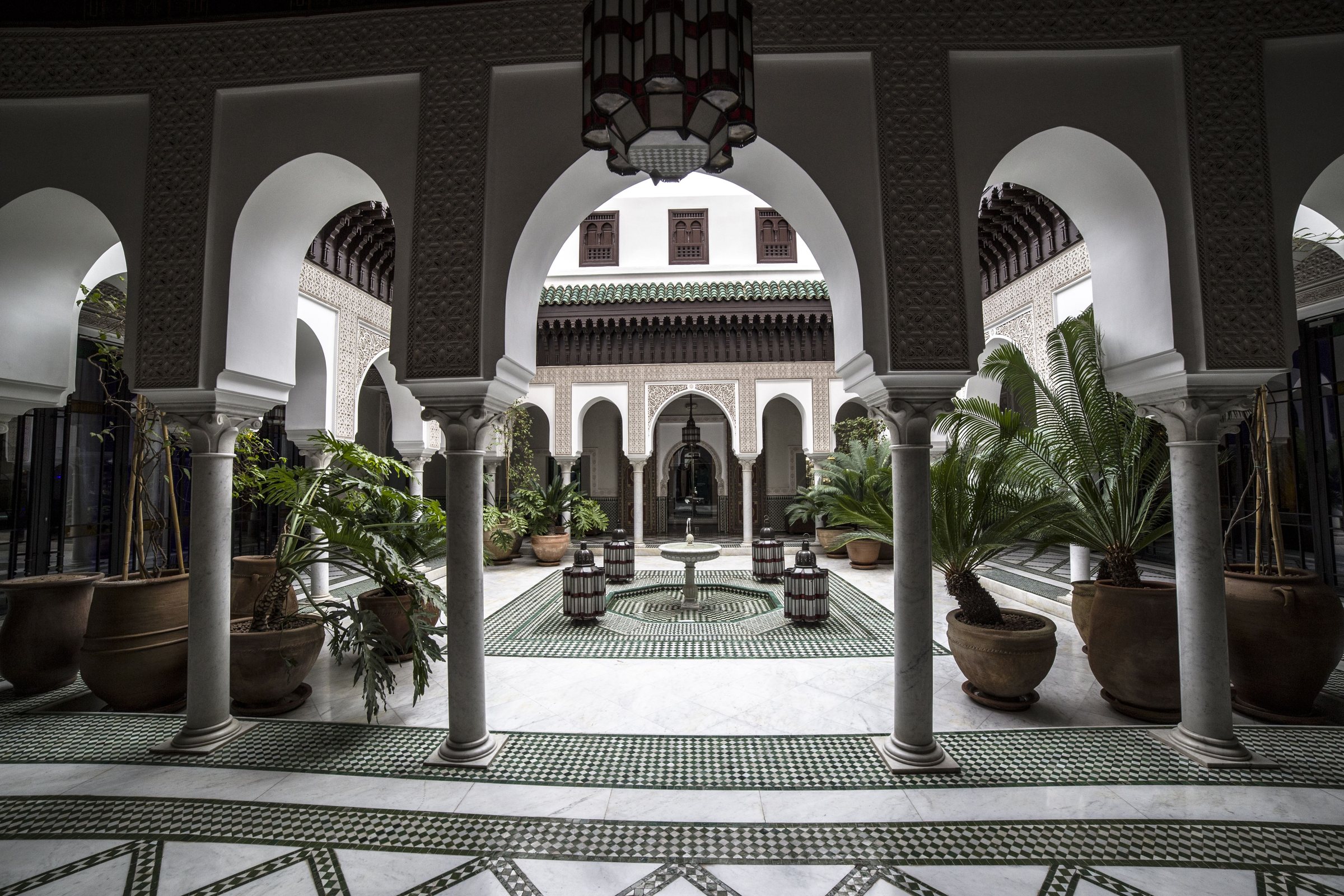Cour intérieure d'un palais marocain avec arcades, fontaine et zellige