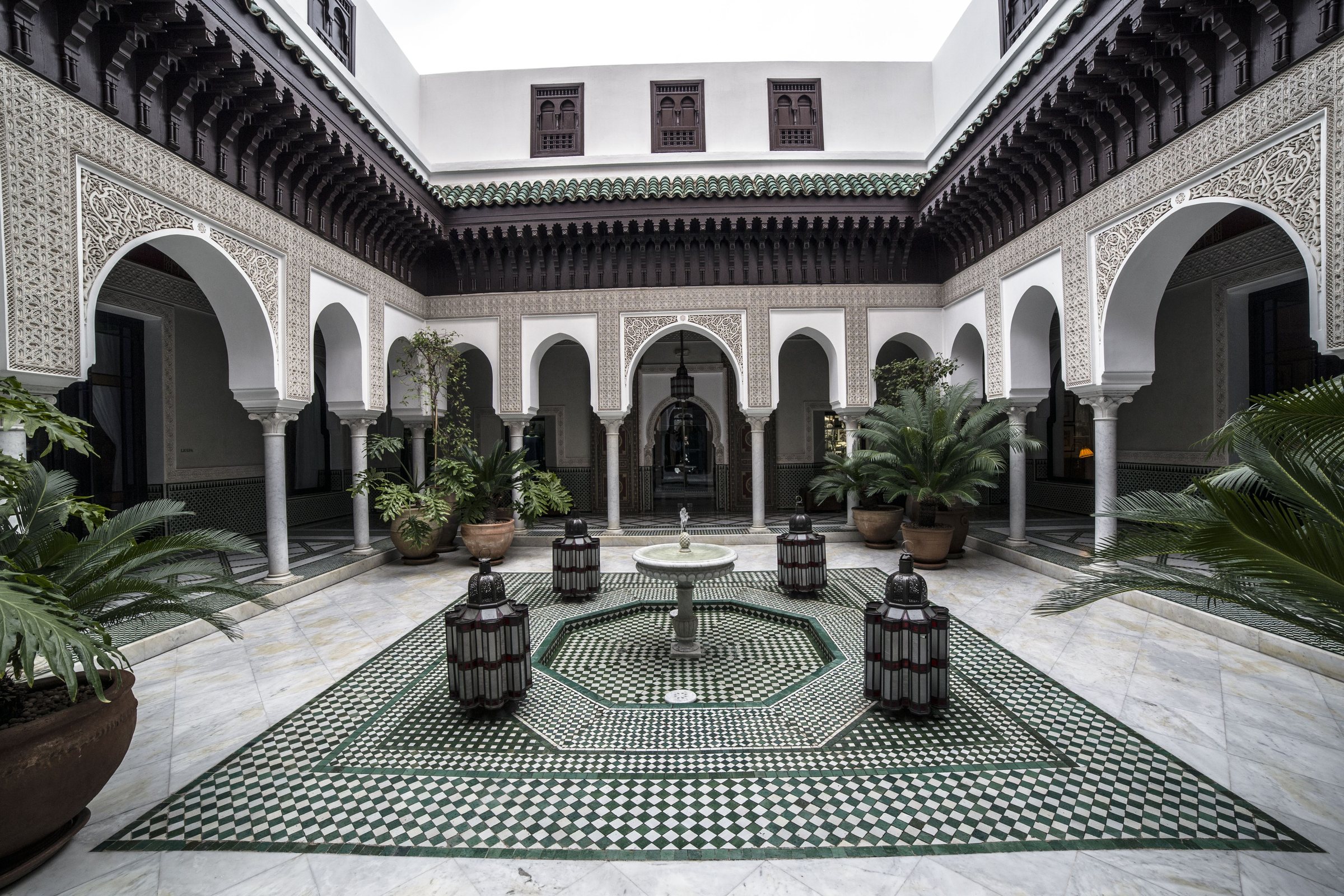 Patio de riad, arcades blanches, sol en zellige, fontaine et lanternes