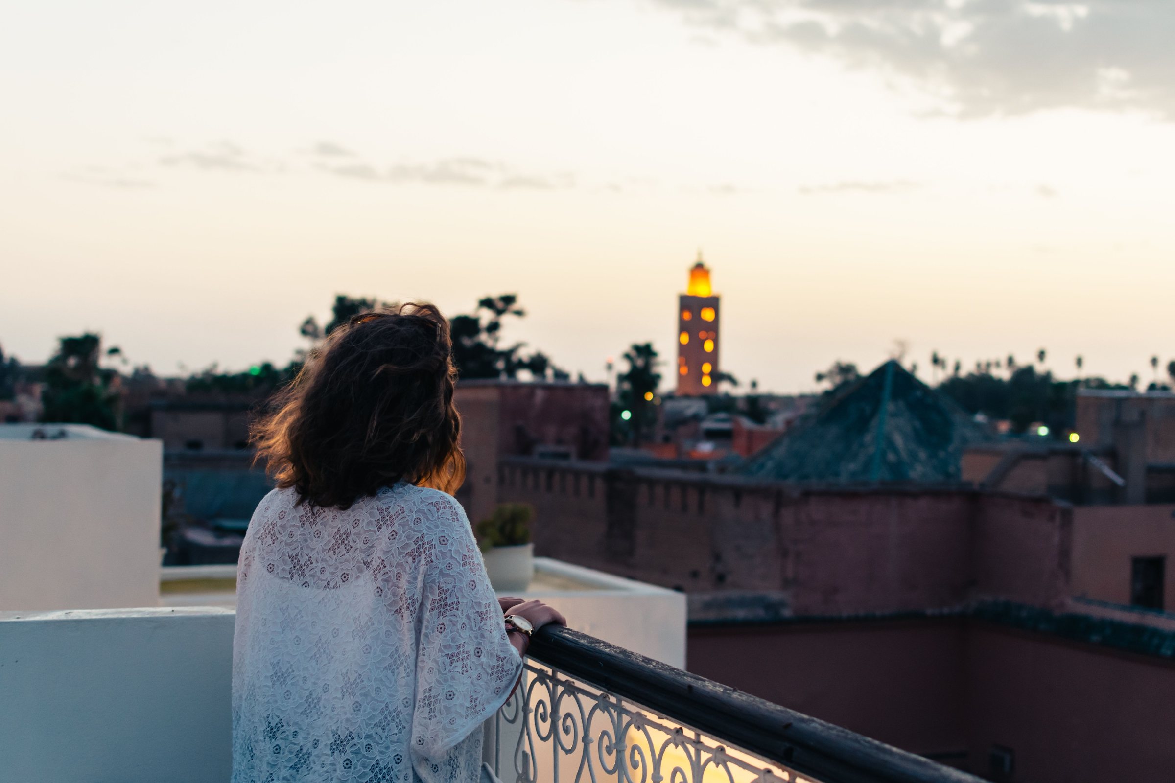 Femme sur un balcon face au minaret de la Koutoubia au crépuscule