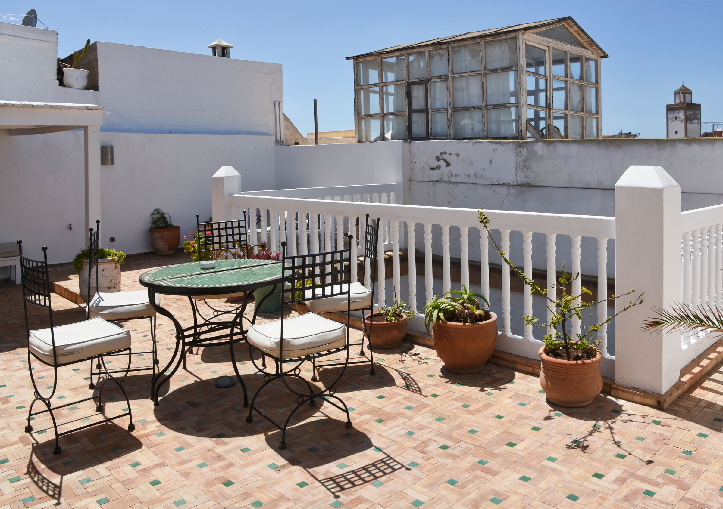 Terrasse sur le toit avec table en fer forgé et plantes, Maroc