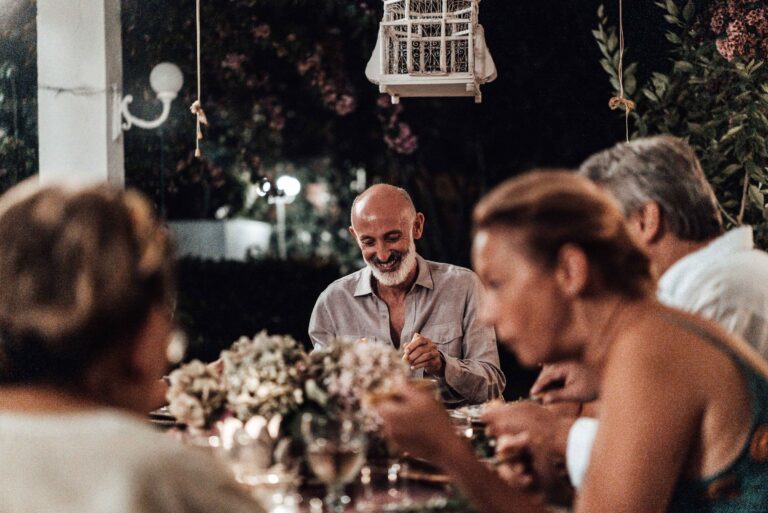 Convives souriants autour d'un dîner en terrasse le soir