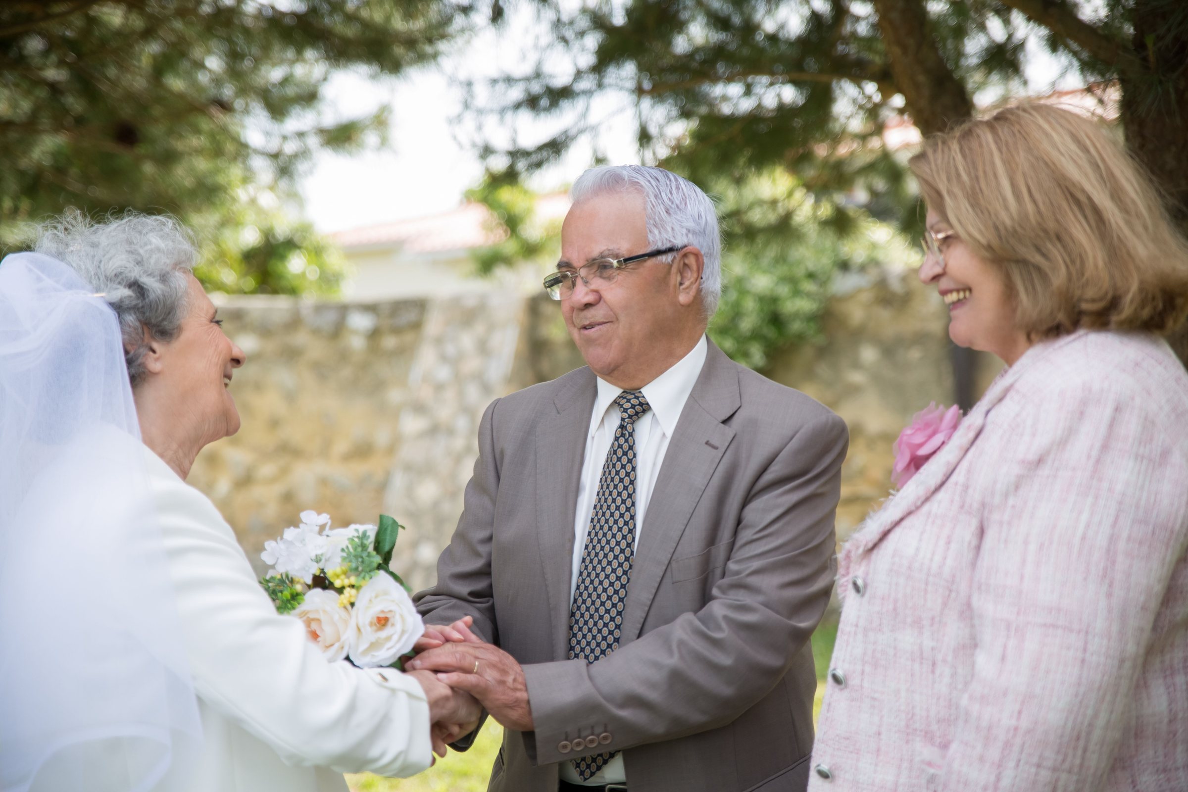 Mariés âgés accueillis par une invitée dans un jardin