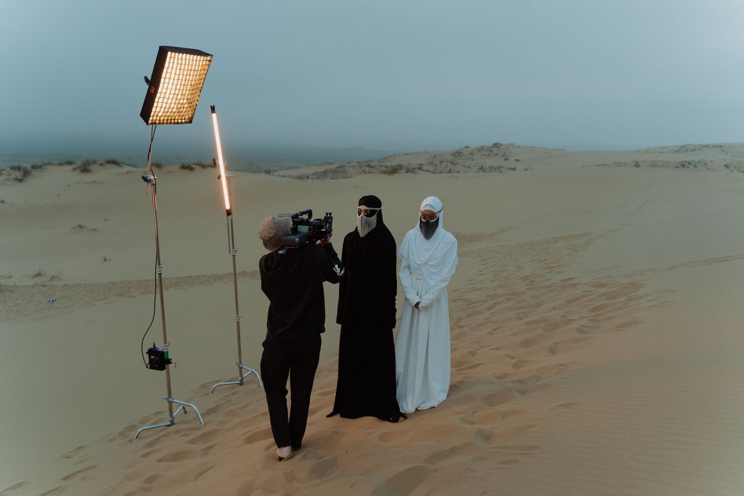 Tournage dans le désert avec projecteur et deux personnes en tenue traditionnelle